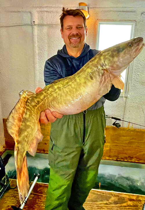image of ice fisherman holding giant eelpout caught at the Northwest Angle